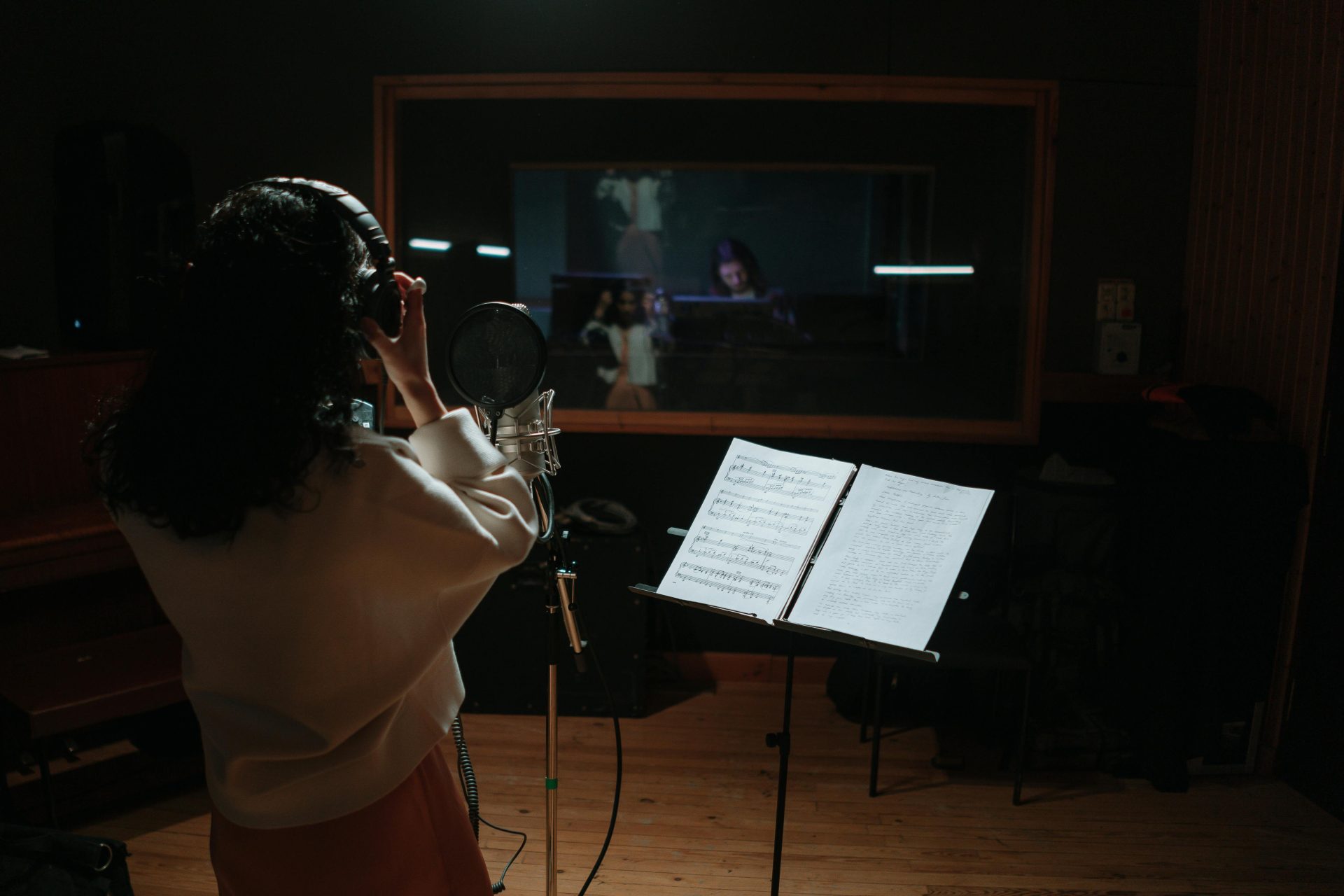 Eine Sängerin nimmt ihren Gesang in einem professionellen Musikstudio mit Mikrofon und Noten auf.