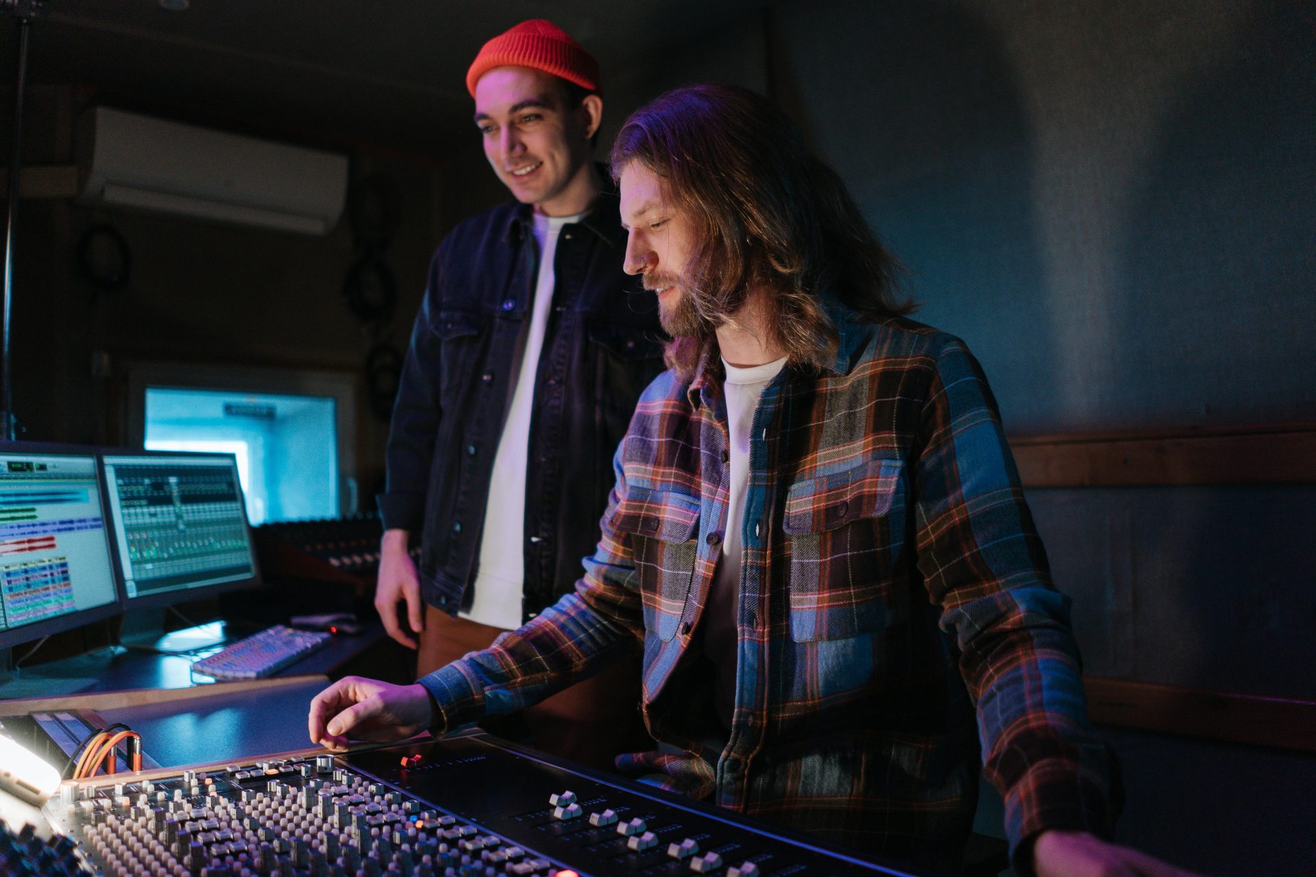 Zwei Toningenieure arbeiten an einem Mischpult in einem professionellen Musikstudio zusammen.